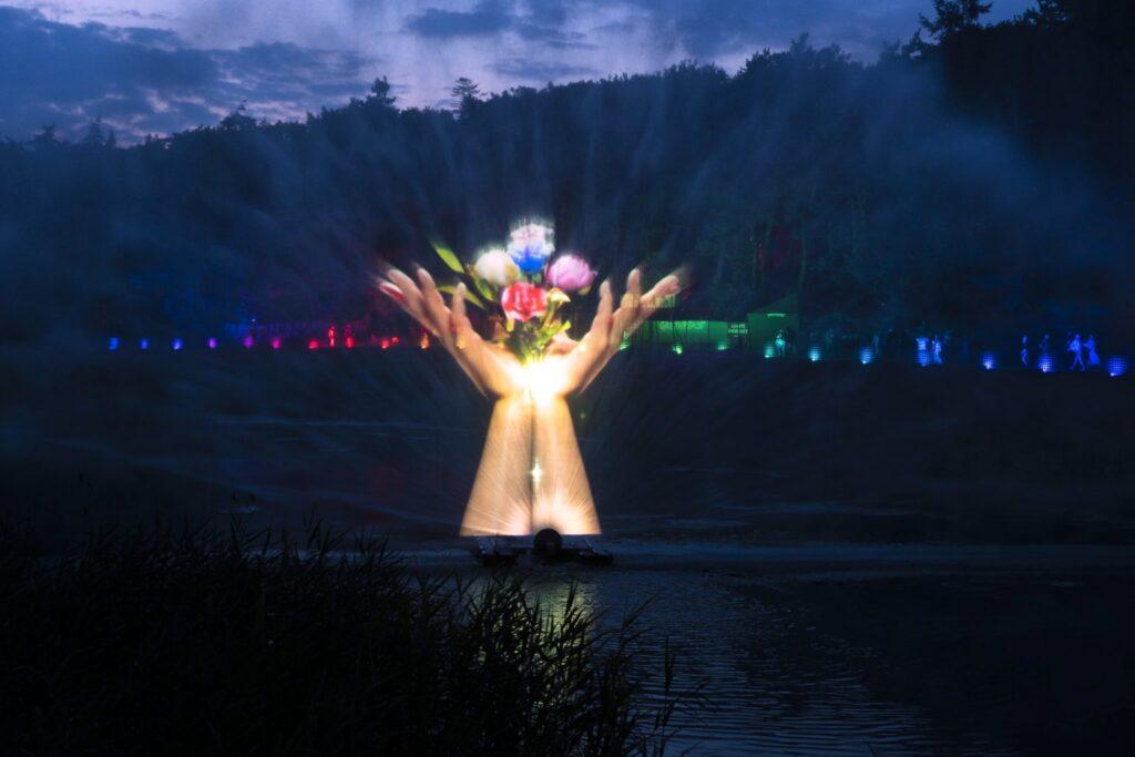 Light projection of hands and flowers over water