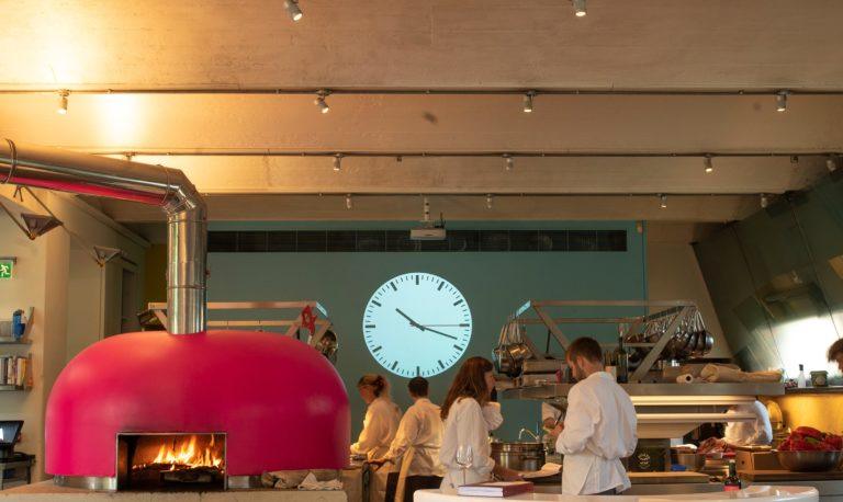 Projection of a clock on a green walk with a pink pizza stove and caterers