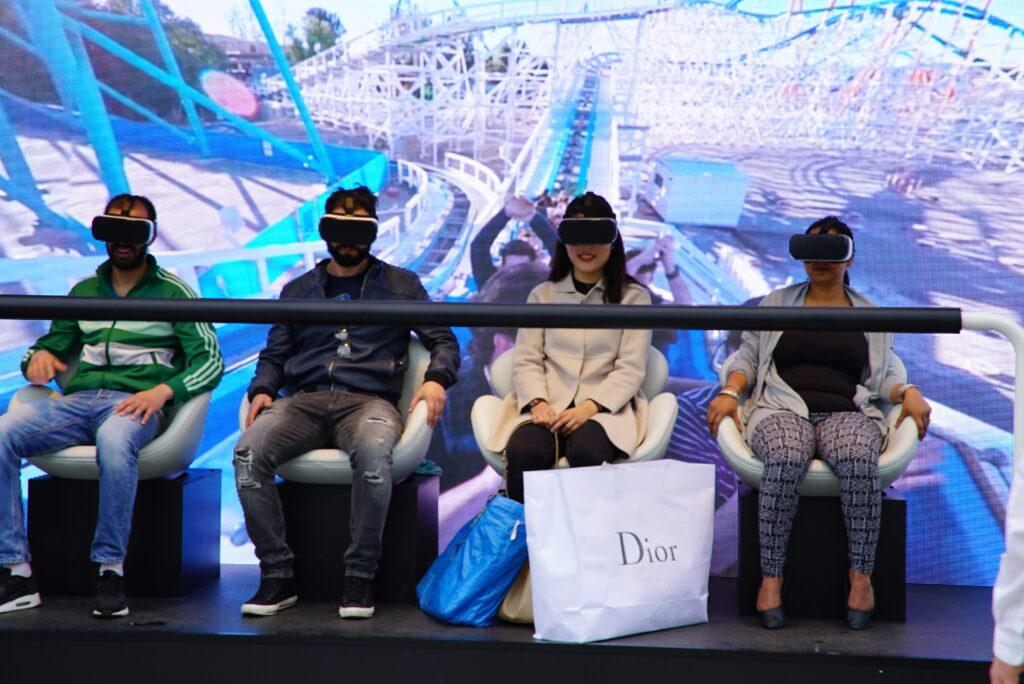 A group of people sat down wearing VR headsets with rollercoaster simulation